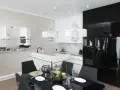 Elegancki styl glamour salonu z kuchnią. Kryształowe lampy, czarne meble i marmurowe detale tworzą luksusową atmosferę.