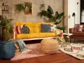 Przytulny salon boho z żółtą kanapą, mnóstwem roślin i etnicznymi dodatkami.