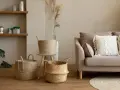 Przytulny salon w stylu boho: plecione kosze, sofa z makramową poduszką i drewniane półki tworzą ciepłą atmosferę.