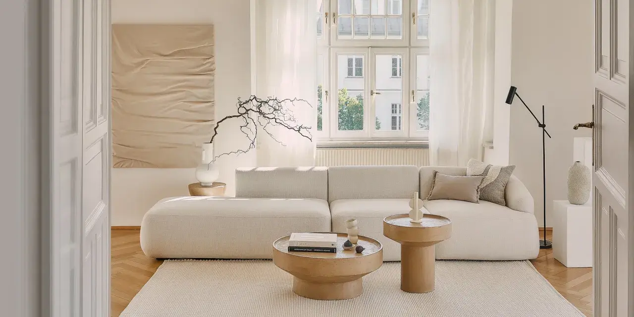 Jasny salon w stylu klasycznym wnętrza. Miękka sofa, drewniane stoliki i subtelna sztuka tworzą przytulną atmosferę.
