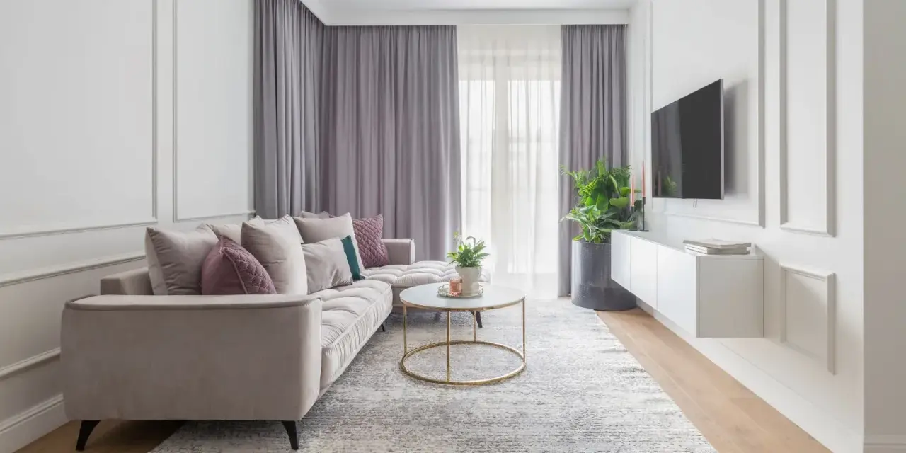 Eleganckie mieszkanie w stylu modern classic z jasną sofą, złotym stolikiem i dekoracyjnymi sztukateriami na ścianach.