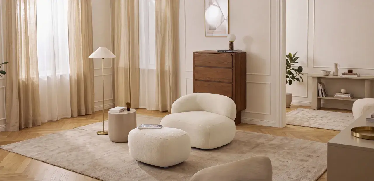 Miękkie meble w kolorze waniliowym tworzą przytulną atmosferę. Wnętrze rozświetlają jasne zasłony i elegancka lampa.