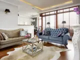 Elegancki salon w stylu nowojorskim z dwoma sofami, szklanym stolikiem i kominkiem.