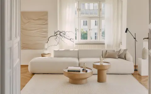 Jasny salon w stylu klasycznym wnętrza. Miękka sofa, drewniane stoliki i subtelna sztuka tworzą przytulną atmosferę.