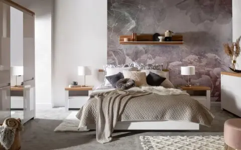 Przytulna sypialnia inspiracje: łóżko z miękkim kocem i ozdobnymi poduszkami, kwiatowa tapeta, drewniana półka, szafki nocne z lampkami.