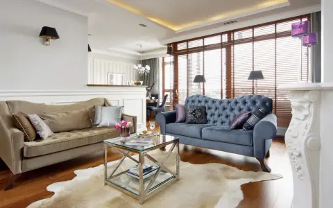 Elegancki salon w stylu nowojorskim z dwoma sofami, szklanym stolikiem i kominkiem.