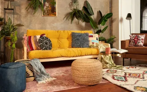 Przytulny salon boho z żółtą kanapą, mnóstwem roślin i etnicznymi dodatkami.