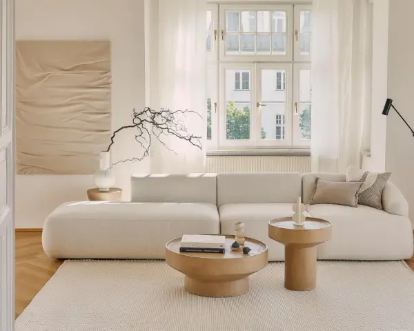 Jasny salon w stylu klasycznym wnętrza. Miękka sofa, drewniane stoliki i subtelna sztuka tworzą przytulną atmosferę.