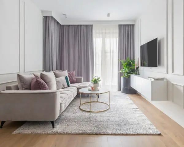 Eleganckie mieszkanie w stylu modern classic z jasną sofą, złotym stolikiem i dekoracyjnymi sztukateriami na ścianach.