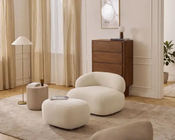Miękkie meble w kolorze waniliowym tworzą przytulną atmosferę. Wnętrze rozświetlają jasne zasłony i elegancka lampa.