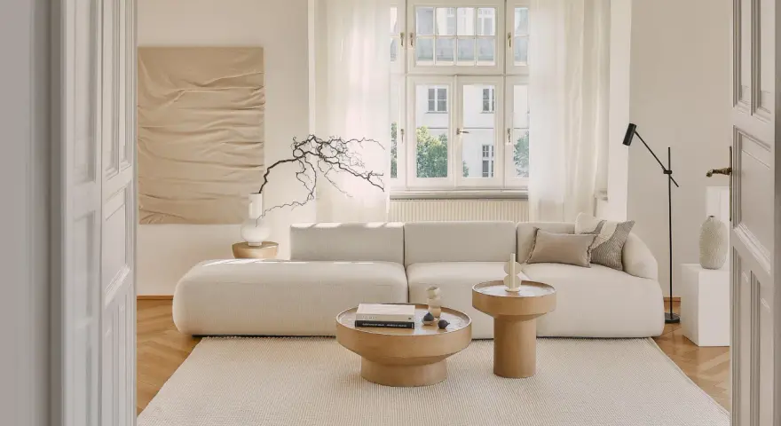 Jasny salon w stylu klasycznym wnętrza. Miękka sofa, drewniane stoliki i subtelna sztuka tworzą przytulną atmosferę.