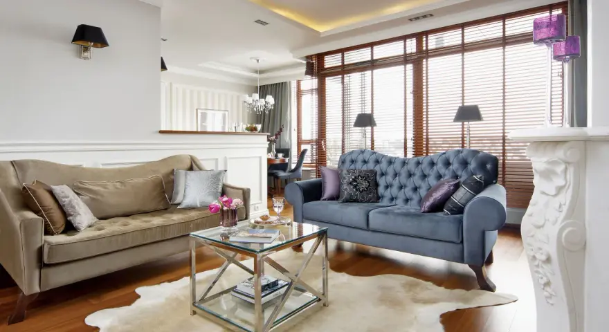 Elegancki salon w stylu nowojorskim z dwoma sofami, szklanym stolikiem i kominkiem.