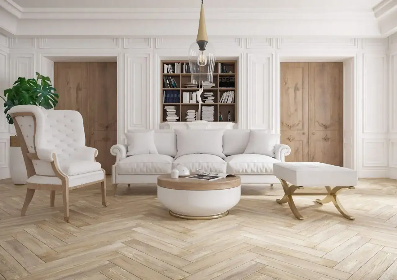 Elegancki salon w stylu klasycznym: biała sofa, fotel uszak, stolik kawowy, puf i regał z książkami.