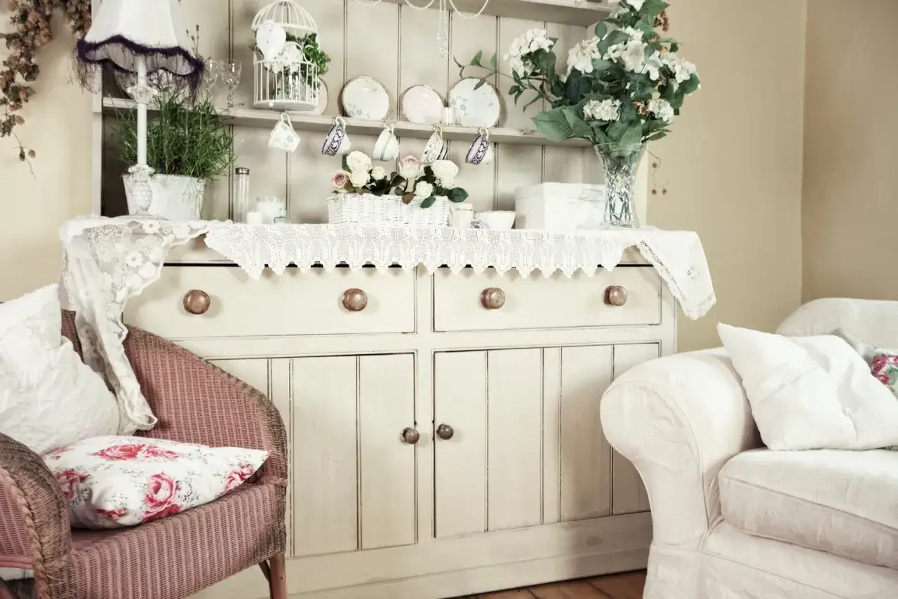 Urocza komoda w stylu shabby chic, ozdobiona koronkami, kwiatami i porcelaną. Wygodny fotel i kanapa zapraszają do odpoczynku.